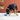 Dog playing with Kong Rewards Tipsy Treat Dispenser toy a blue toy on a concrete surface against a red brick wall.